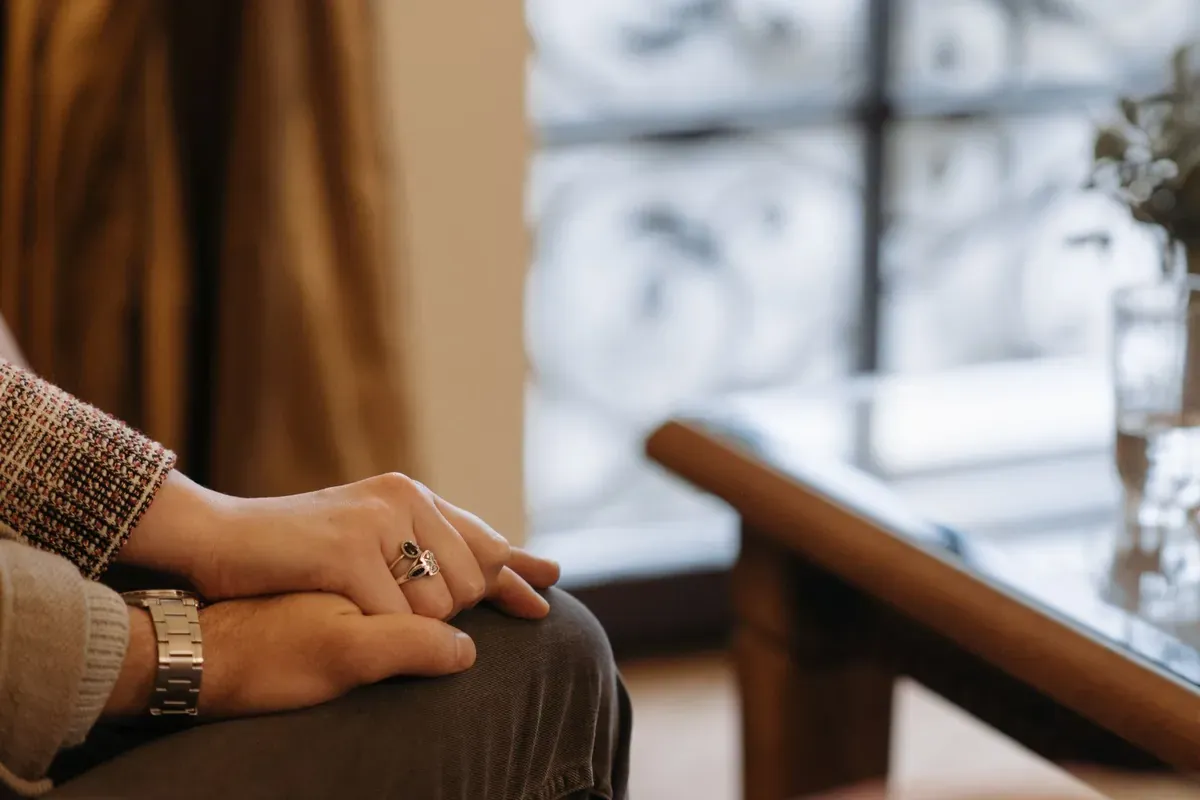 One person resting a hand over another's at home, a quiet gesture of support